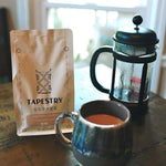 12 oz bag of abstract blend on wood table with french press and mug of coffee