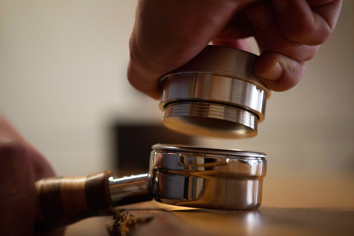 Barista tamping espresso during hands-on barista training.